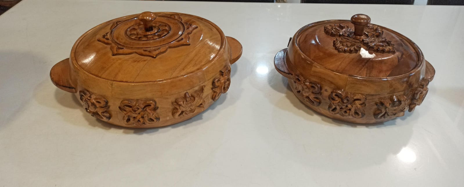 Two wooden carvings with lids on a white surface